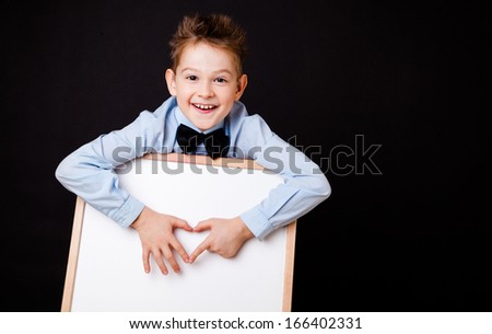 Portrait of cheerful boy pointing on white banner on the black background