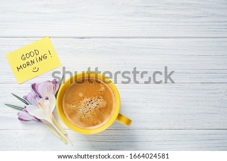 Delicious coffee, flowers and card with GOOD MORNING wish on white wooden table, flat lay. Space for text