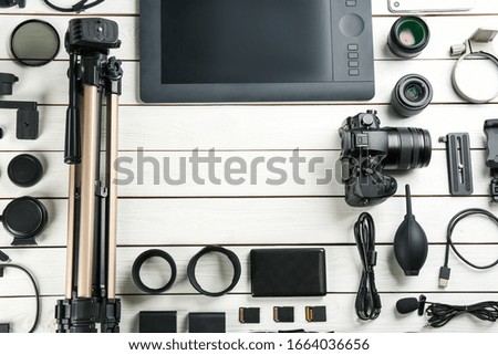 Flat lay composition with camera and video production equipment on white wooden table. Space for text