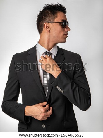 Attractive young man in business suit and sunglasses looking camera right creating profile on white background 