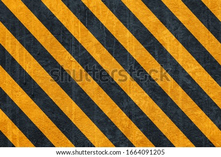 black and yellow safety hazard attention warning stripes on cement wall