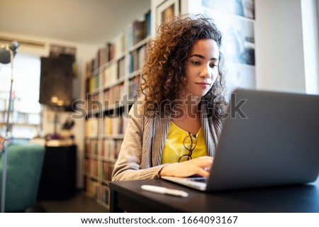 Young beautiful student girl working, learning in college library Royalty-Free Stock Photo #1664093167