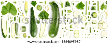 Large collection of green zucchini vegetable pieces, slices and leaves isolated on white. Top view. Seamless abstract background.