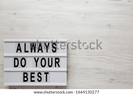 'Always do your best' words on a lightbox on a white wooden background, top view. Overhead, from above, flat lay. Copy space.