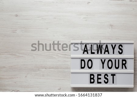 'Always do your best' words on a lightbox on a white wooden surface, top view. Overhead, from above, flat lay. Space for text.
