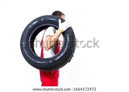 Mechanic carrying a tyre on a white background