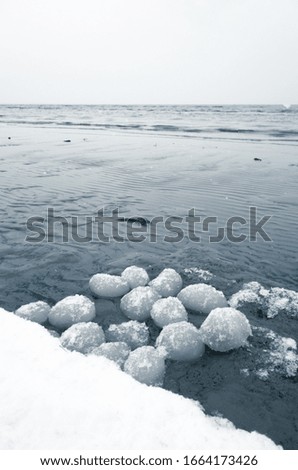 Ice balls of natural origin, icy coast of Gulf of Finland, Russia. Blue toned vertical photo