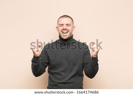 young handsome man looking extremely happy and surprised, celebrating success, shouting and jumping against flat wall