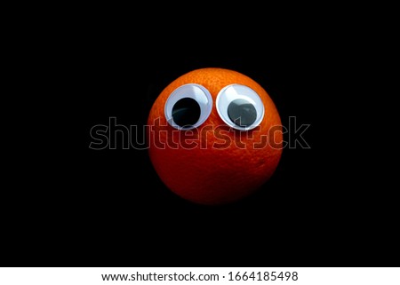 orange with eyes on a black background
