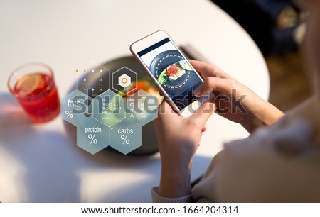 food, new nordic cuisine, technology and people concept - close up of hand with toast skagen on smartphone screen and nutritional value chart at restaurant