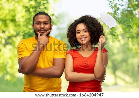 relationships and people concept - happy smiling african american couple with little blank speech bubble over green natural background