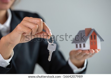 Your new house, real estate agent holding house key to his client after signing contract agreement in office,concept for real estate, renting property