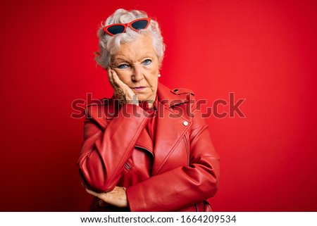 Senior beautiful grey-haired woman wearing casual red jacket and sunglasses thinking looking tired and bored with depression problems with crossed arms.