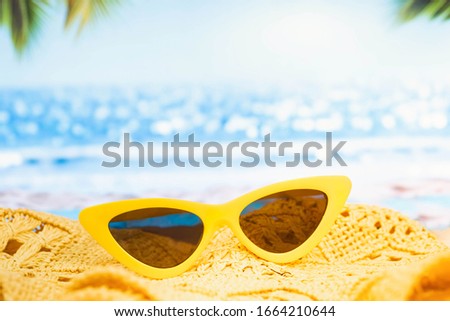 Beach, yellow sunglasses and hat on the sand against  sea and sky.Tropical summer vacation concept. Sunny day on the beach,Selective focus