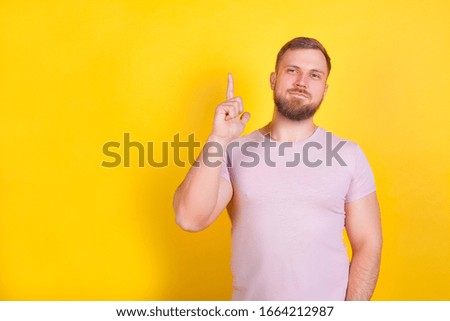 A man with his index finger raised up, on a yellow background, to the right of the text space, with copy space. The concept is an important idea, choice or decision, important information.