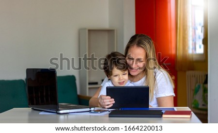 Happy laughing single mother and little preschool cute son using laptop online application,making video call,having fun,babysitter teaching small boy use computer,watching cartoons together.Copy space