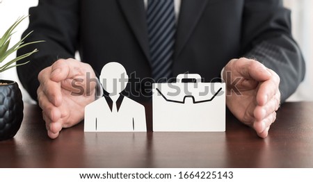 Insurer protecting an employee and a briefcase with his hands Royalty-Free Stock Photo #1664225143