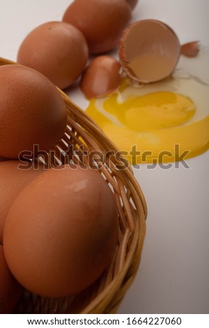 Chicken eggs in a wicker basket , broken egg and eggs scattered on a white background. Close up.
