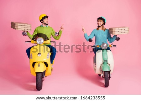 Full size photo of funny lady guy drive two vintage moped carry paper pizza boxes direct finger empty space courier wear casual outfit headgear isolated pink color background