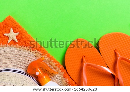 Summer beach flat lay accessories. Sunscreen bottle cream, straw hat, flip flops, towel and seashells on colored Background. Travel holiday concept with copy space.