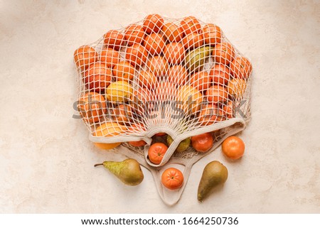 Cotton mesh shopping bag with fruit on background. Zero waste concept. Green, ecology.