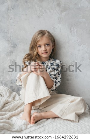 
Beautiful charming girl child 7 years old. smiling, looking at the camera. Stylishly fashionably dressed in white trousers and a shirt.