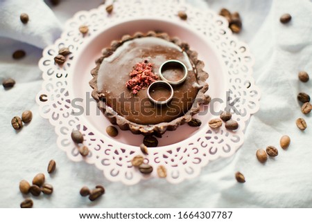 Platinum or silver wedding rings on the tasty chocolate tart with coffee beans