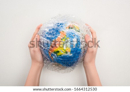 Cropped view of woman holding globe in plastic bag on white background, global warming concept