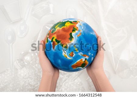 Cropped view of woman holding globe above plastic garbage on white background, global warming concept