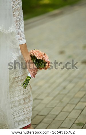 bride in a white dress holds in his hands a bouquet of pink tsveto. the bride holds a pink wedding bouquet in her hands. close-up photo