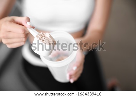Sporty young woman with protein at home, closeup Royalty-Free Stock Photo #1664339410