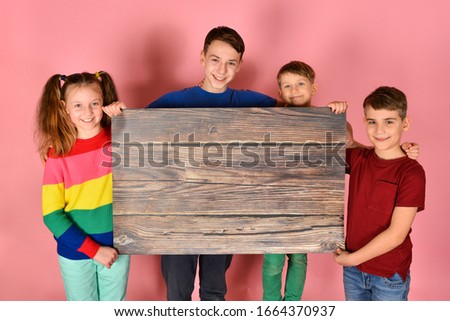 Two boys and a girl are holding a blank poster for inscription and text.