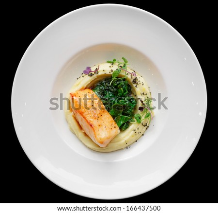 Fried fish fillet with potato mash isolated on black background