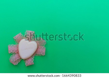 Minimalistic green background with white heart with text I love you lie on pink ribbon. Picture with copy space, top view
