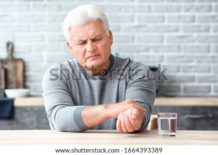 Senior man suffering from Parkinson syndrome at home Royalty-Free Stock Photo #1664393389