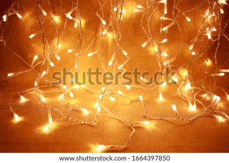 Light garlands lying on a golden wrapping paper background