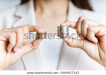 Hands compare two piles of coins of different sizes. Royalty-Free Stock Photo #1664427163
