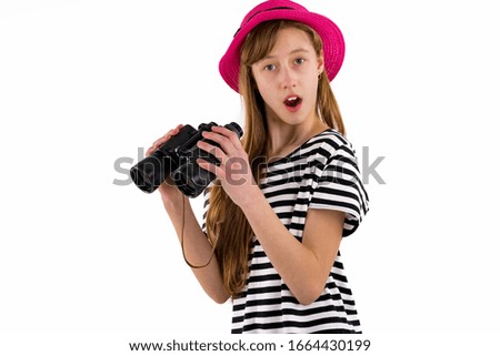 Portrait of slim trendy surprised young girl in striped t-shirt and wearing red hat with binocular on isolated white background.Copy space,mock up banner.Summer concept.