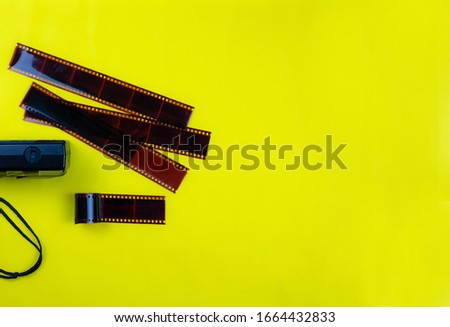 Top view of manual old camera lies and film used to strip at yellow background