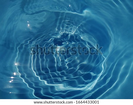 The​ abstract​ of​ surface​ blue​ water​ in​ the​ swimming​ pool​ reflected​ with sunlight​ for​ background​