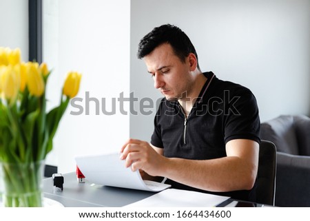 a serious man sits sitting at a table and fills out documents with a pen,filling out documents,remote business,self employed,working person for documents