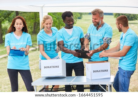 Volunteer group volunteer in fundraiser with donation box Royalty-Free Stock Photo #1664451595