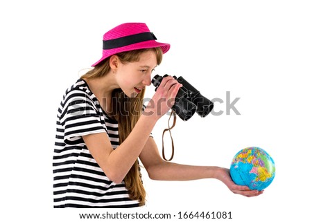 Traveler concept. Caucasian slim surprised trendy colorful teenage girl in summer striped t -shirt, hat looking to globe with binoculars isolated on white background.travel on weekends getaway.