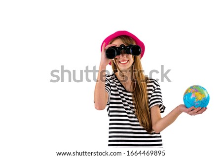 Traveler concept. American slim smiling trendy teenage girl in summer striped t-shirt, hat globe looking to you with binoculars isolated on white background.travel on weekends getaway.Copy space.