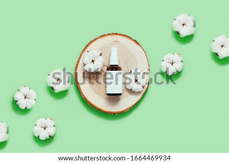 Zero waste picture with spray glass bottle on wooden tray with cotton flowers on mint green background. Flat lay, top view, copy space.