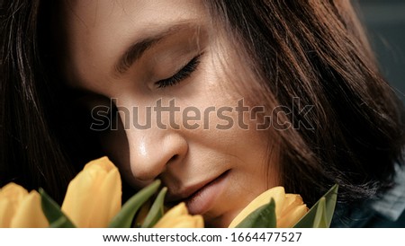 Girl with flowers, attractive young woman sniffs yellow tulips. International Womens Day, Valentines Day, date, anniversary, March 8, February 14, birthday concept. Close up