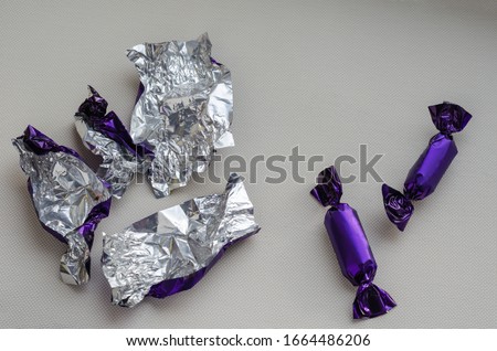 Two chocolate candies and candy wrappers. The last uneaten treats and a bunch of empty wrappers on a light background. View from above. Close-up. Selective focus. Royalty-Free Stock Photo #1664486206
