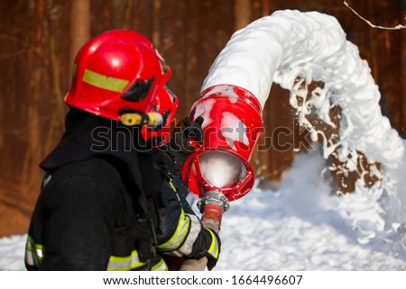 Firefighters extinguish a fire. Rescuers with fire hoses with foam.