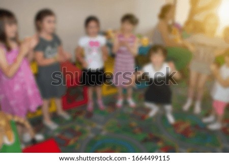 Dancing kids at birthday party in kindergarten. Blurred image for background use.