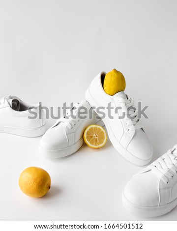Fashionable women's sneakers, a yellow lemon on white background. Healthy lifestyle concept. Flatlays. Fashion shoes